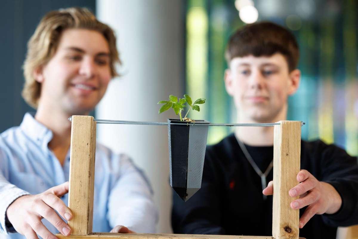 Two students hold on to a small planting created as part of an innovation presentation